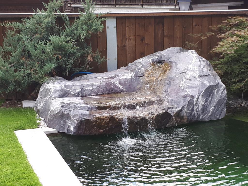 Wasserfall im Naturpool mit einem Natursteinblock